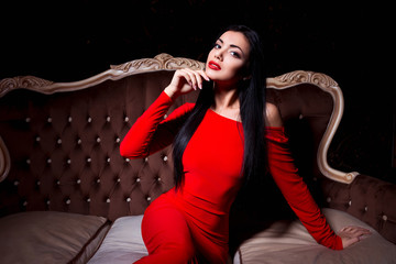 Elegant woman with make up wearing red dress posing in a sensual