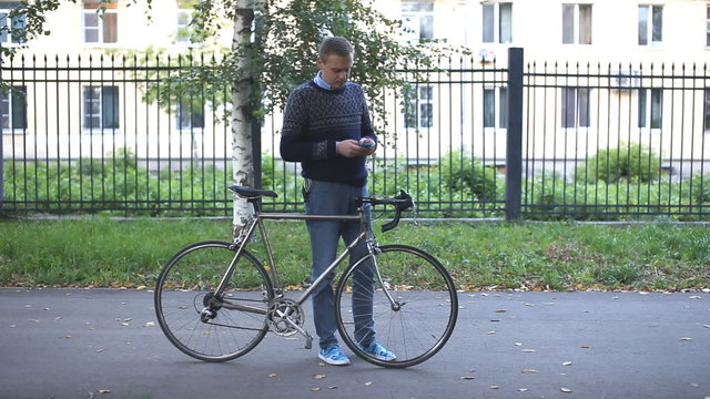 man with bicycle looking at phone