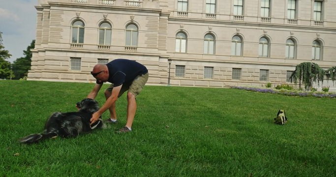Man Plays with Dog on the Lawn of the Library of Congress in Washington DC