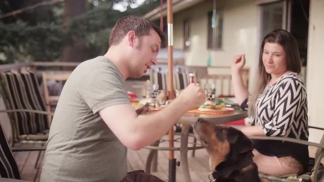A man training his dog to sit with a piece of hamburger
