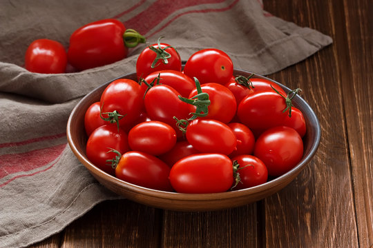 Tomatoes / Fresh red cherry tomatoes in ceramic bowl on rustic wooden table