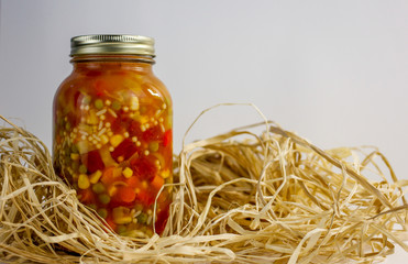 jar of vegetable soup on a white background with raffia 