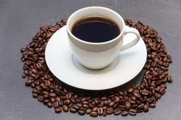 Kaffetasse mit Kaffeebohnen auf Schiefertafel