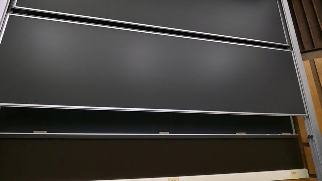 A large chalkboard rises in front of a university's classroom.