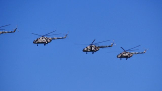 Four helicopters fly in the sky in row
