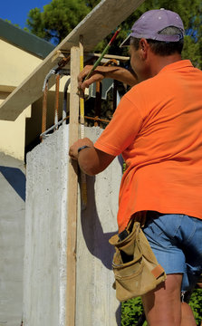 worker with pencil and  folding ruler wooden meter track a measurement on a concrete pillar