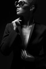 Portrait of a beautiful girl posing in studio in black jacket and fashion sunglasses. The concept...