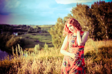 Obraz premium Young red-haired woman on the rock near river is fashionable