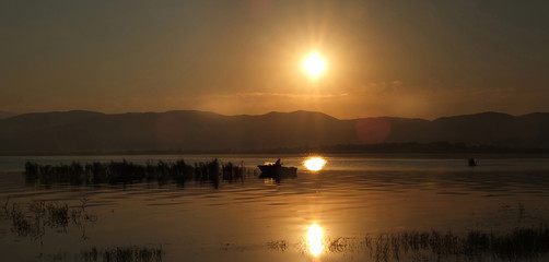 Sunrise  over Dojran Lake and fisherman between reeds