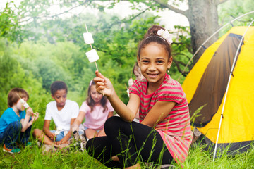 Happy African girl holding stick with marshmallow 