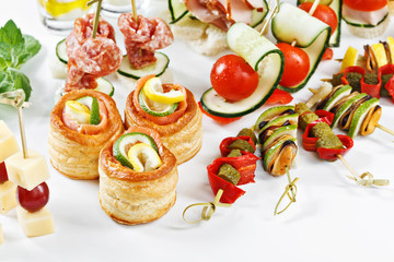 close-up view set of canapes with vegetables, salami, seafood, meat and decoration on whie plate studio isolated