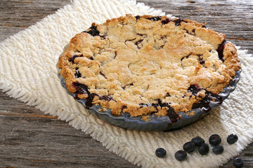 Blueberry pie on rustic wooden table with place mat