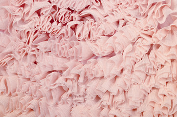 Close up on pink lace. Pastel pink crumpled tulle as background.