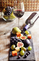 Red wine, grapes, cheese, figs, walnuts and cashews on black cheese board. Selective focus