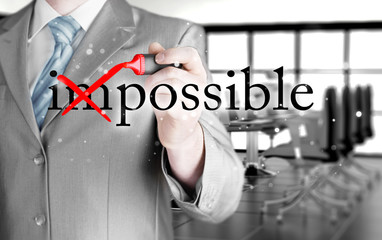 Businessman Hand turning the word Impossible into Possible with