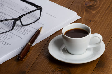 Documents with pen, glasses and coffee cup