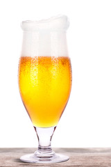Frosty glass of light beer on a wooden table