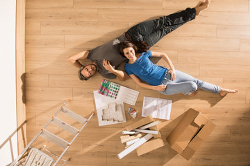 Top view, a modern couple lying on the floor of their new home