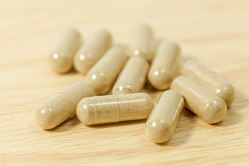 Medical herbal capsules on wood background.