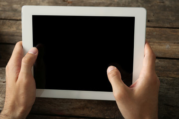 Hands holding digital tablet on wooden table background