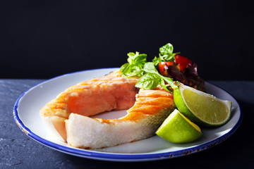 Tasty grilled salmon with lime and salad on table close up