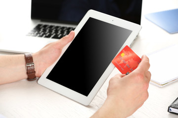 Man holding credit card and tablet on workplace background