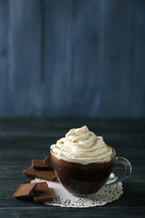 Cup of coffee with cream on color wooden background