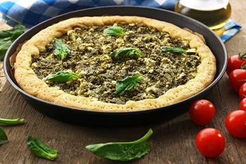 Open pie with spinach and tomato cherry on table close up