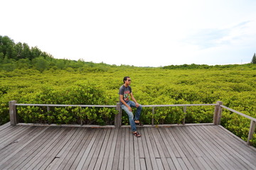 Man and walkway made from wood and mangrove field
