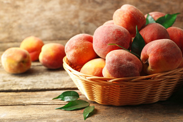 Ripe peaches in basket on wooden background
