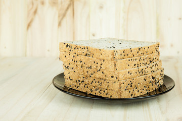 Fresh slices of wholewheat bread with various seeds and multigrain on the black plate in wood background