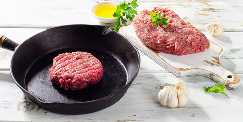 Raw ground beef  patty on pan.