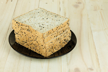 Fresh slices of wholewheat bread with various seeds and multigrain on the black plate in wood background
