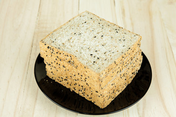 Fresh slices of wholewheat bread with various seeds and multigrain on the black plate in wood background