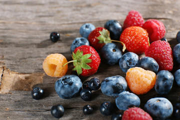 Heap of sweet tasty berries on wooden table close up