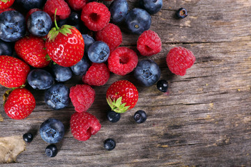 Heap of sweet tasty berries on wooden table close up