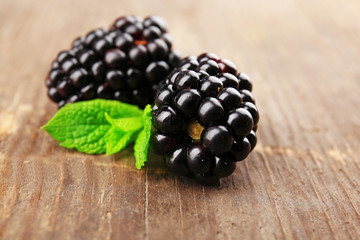 Ripe blackberries with green leaves on wooden background
