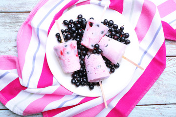 Sweet ice cream with black currants in white plate on striped napkin, closeup