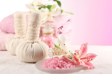 Obraz na płótnie Canvas Massage bags with spa treatment and flowers on wooden table, on light background