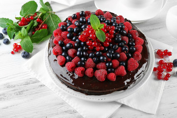 Delicious chocolate cake with summer berries on wooden table, closeup