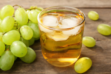Glass of grape juice with ice cubes on wooden table, closeup