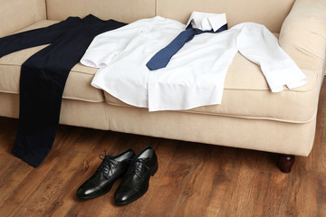 Male clothing on sofa near shoes on floor in room