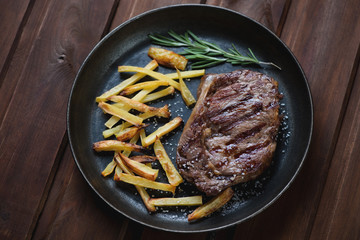 Frying pan with grilled ribeye beef steak and roasted potato