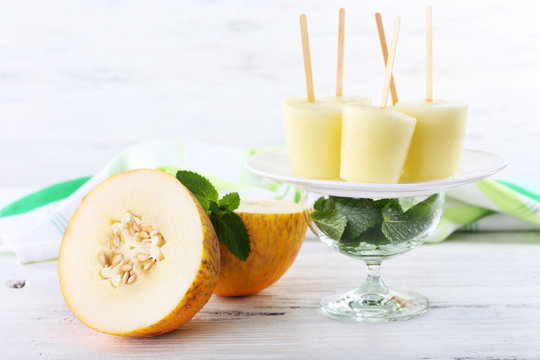 Melon ice lolly on table on light blurred background