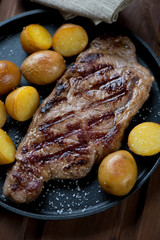 Close-up of grilled striploin steak with potato, selective focus