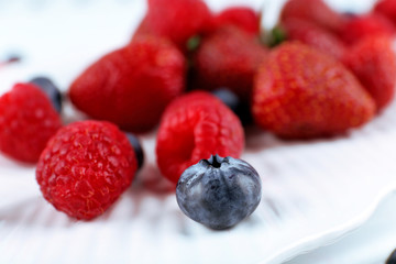 Tasty ripe berries on plate close up