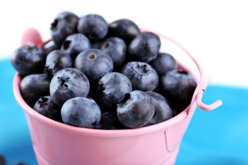 Tasty ripe blueberries in bucket on table close up