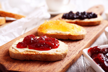 Fresh toast with butter and different jams on table close up