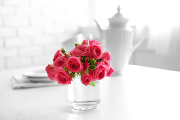 Beautiful flowers in vase on table, on light background