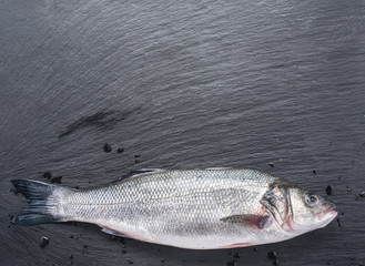 Raw seabass fish on the graphite board.